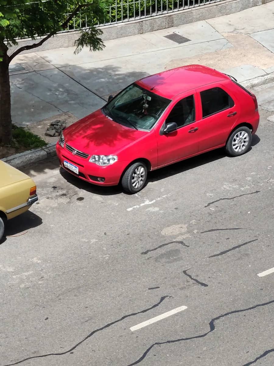 Fiat Palio Fire vermelho visto de frente e de lado em uma rua.