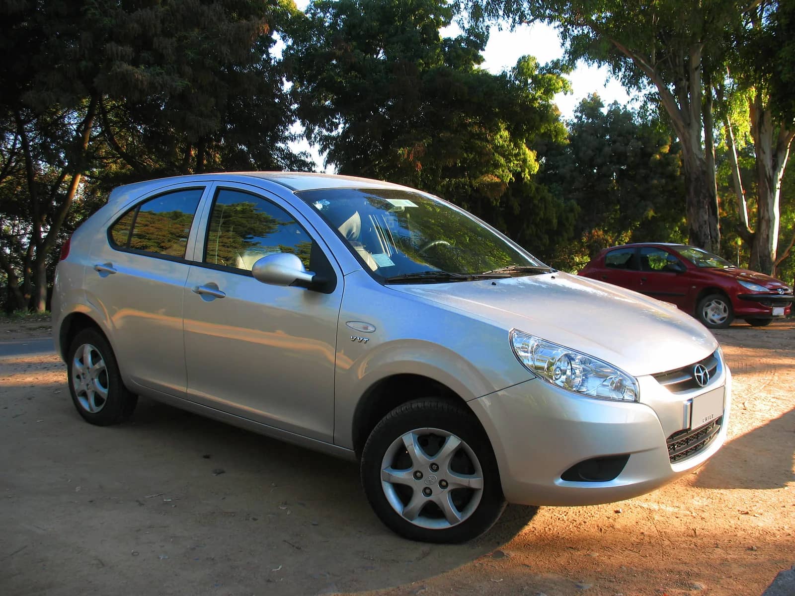 JAC J3 1.3 BE Sport 2013 prata, visto de frente e de lado, estacionado em área arborizada.