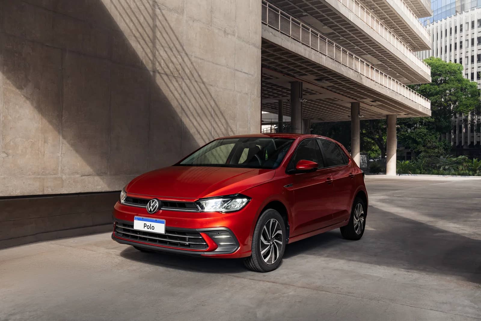 Volkswagen Polo Highline 2025 vermelho visto de frente e de lado em uma área urbana.