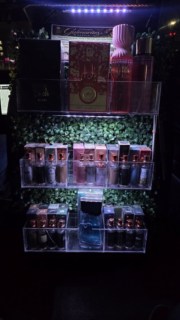Vitrine de perfumes dentro de um carro, com estante acrílica iluminada e produtos organizados por tamanho