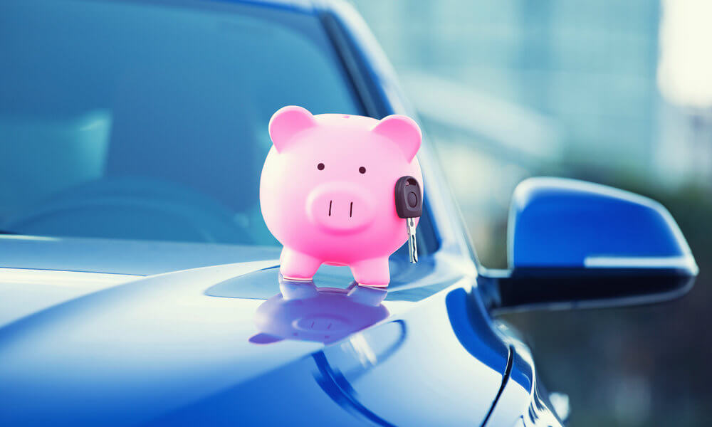 Cofrinho de porquinho dos custos e benefícios junto de uma chave de carro em cima do capô de um carro