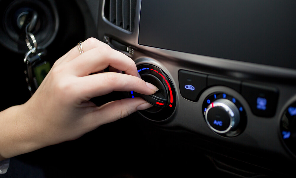 Pessoa regulando a temperatura do ar do condicionado do carro, exemplificando os acessórios essenciais para ser motorista