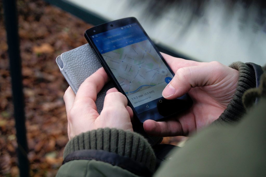 Pessoa segurando celular com as duas mãos acessando GPS.