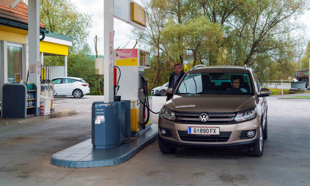 Homem em um posto de gasolina abastecendo um carro pensando em como reduzir o impacto da alta da gasolina