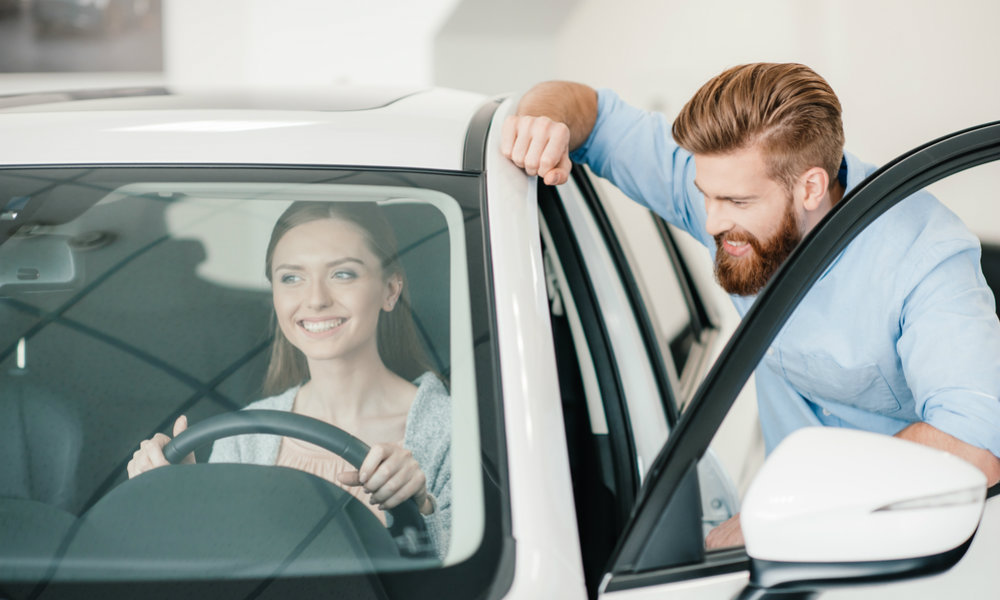 Um homem informando a uma mulher quais são as vantagens de se comprar um carro seminovo