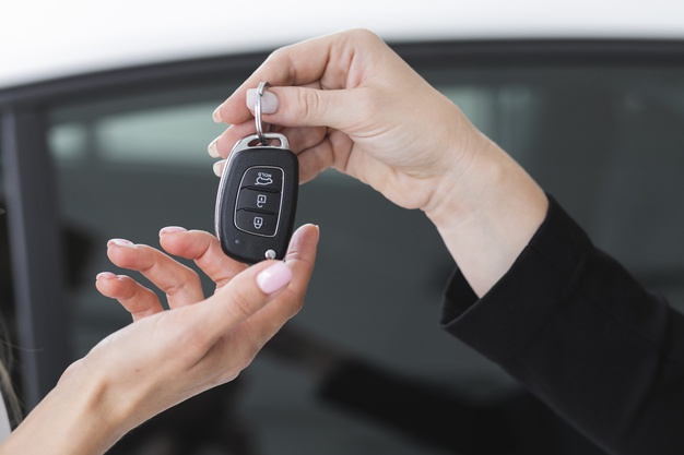 Uma pessoa recebendo a chave de um carro alugado para ser motorista de aplicativo
