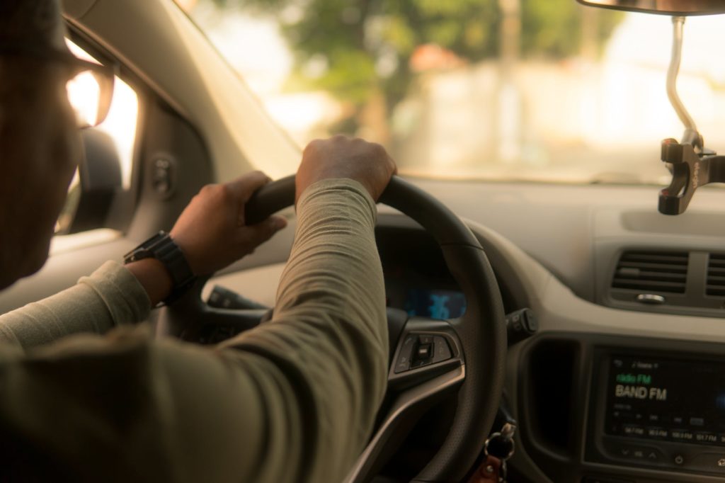 homem segurando o volante com duas mãos aumentando a média de ganho com Uber e 99