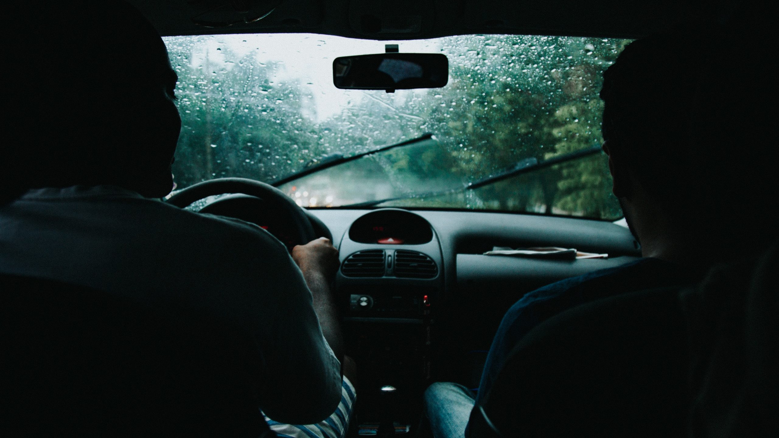 Duas pessoas dentro de um carro em um dia chuvoso ilustrando como receber mais chamadas Uber e 99