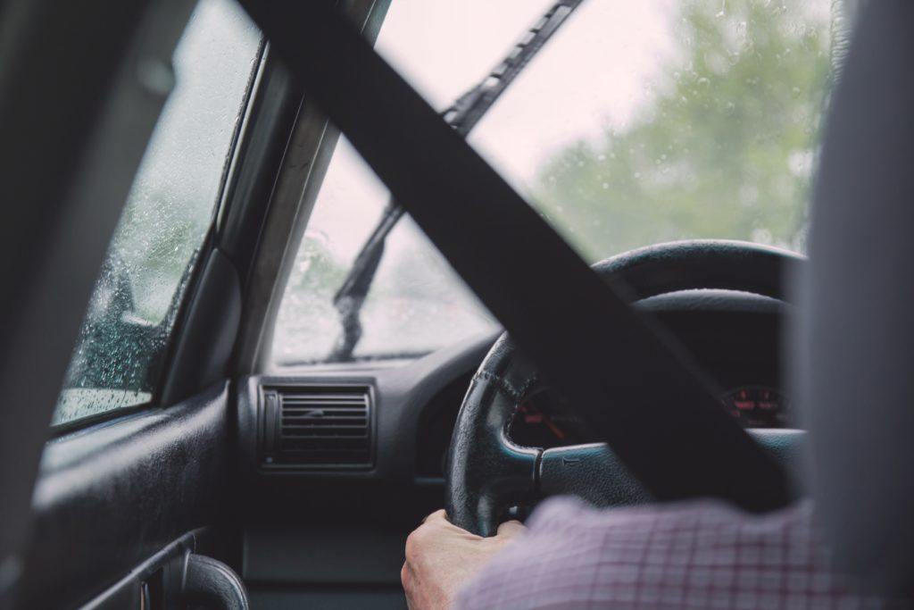 Motorista dirigindo veículo na chuva.