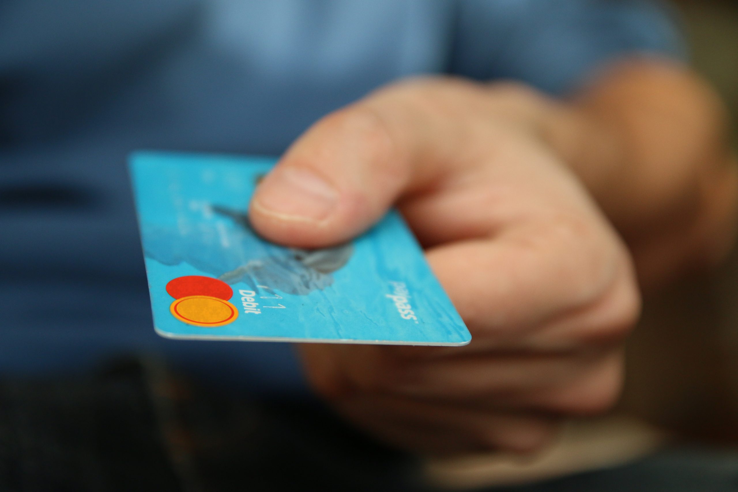 Mão segurando um cartão de crédito azul.