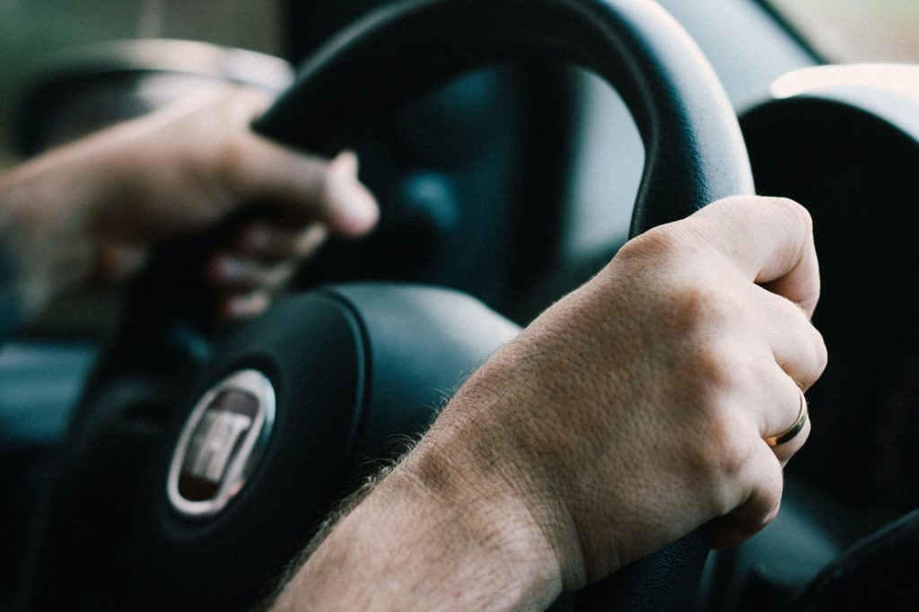 Duas mãos segurando o volante de um carro.