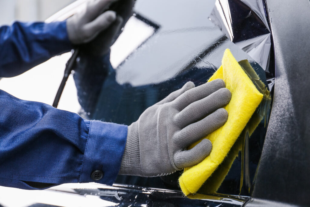 Limpando vidro de veículo com pano amarelo.
