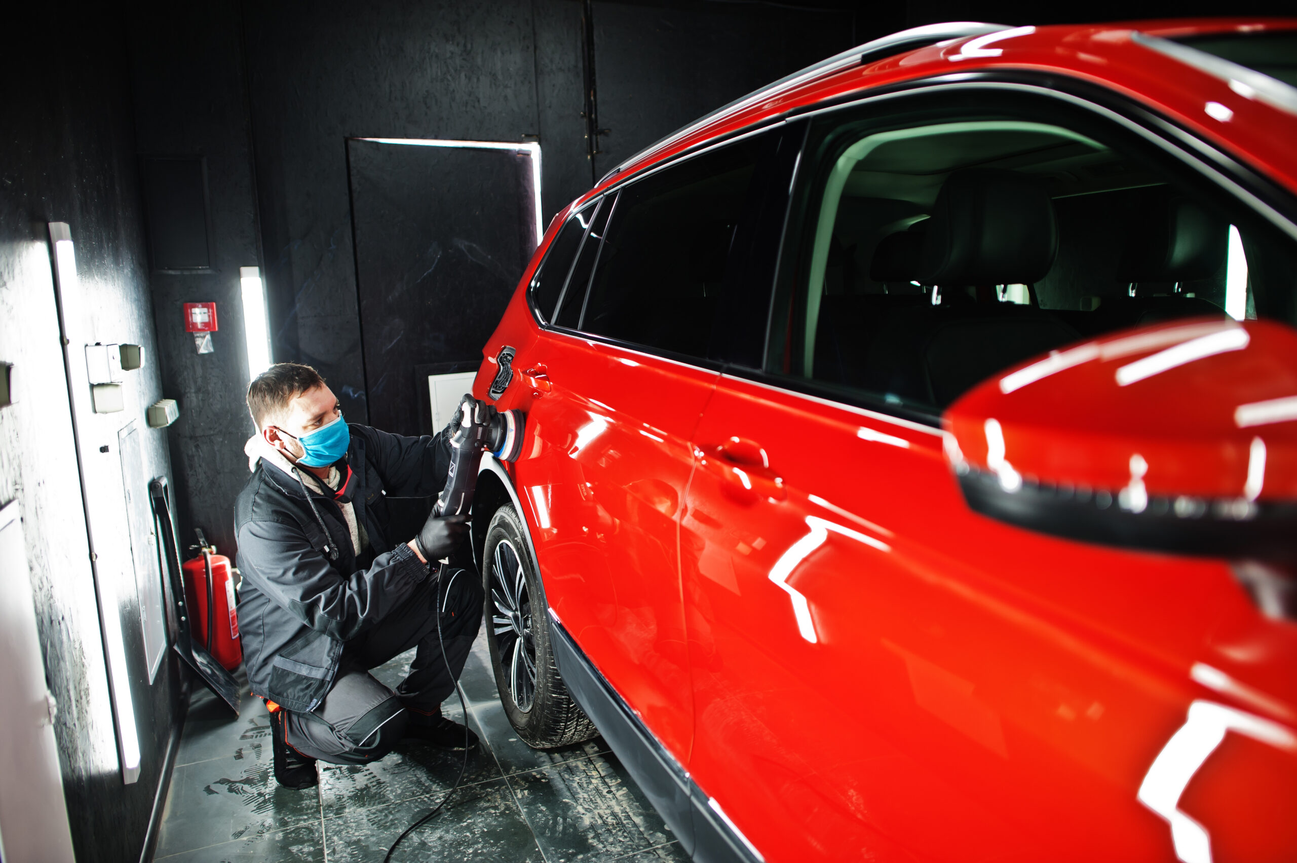 Profissional especializado polindo um carro vermelho após passar pelo processo de vitrificação automotiva.