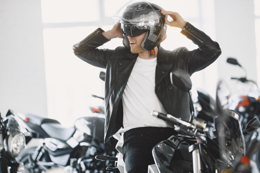 Motociclista retirando capacete, em loja de motocicletas.