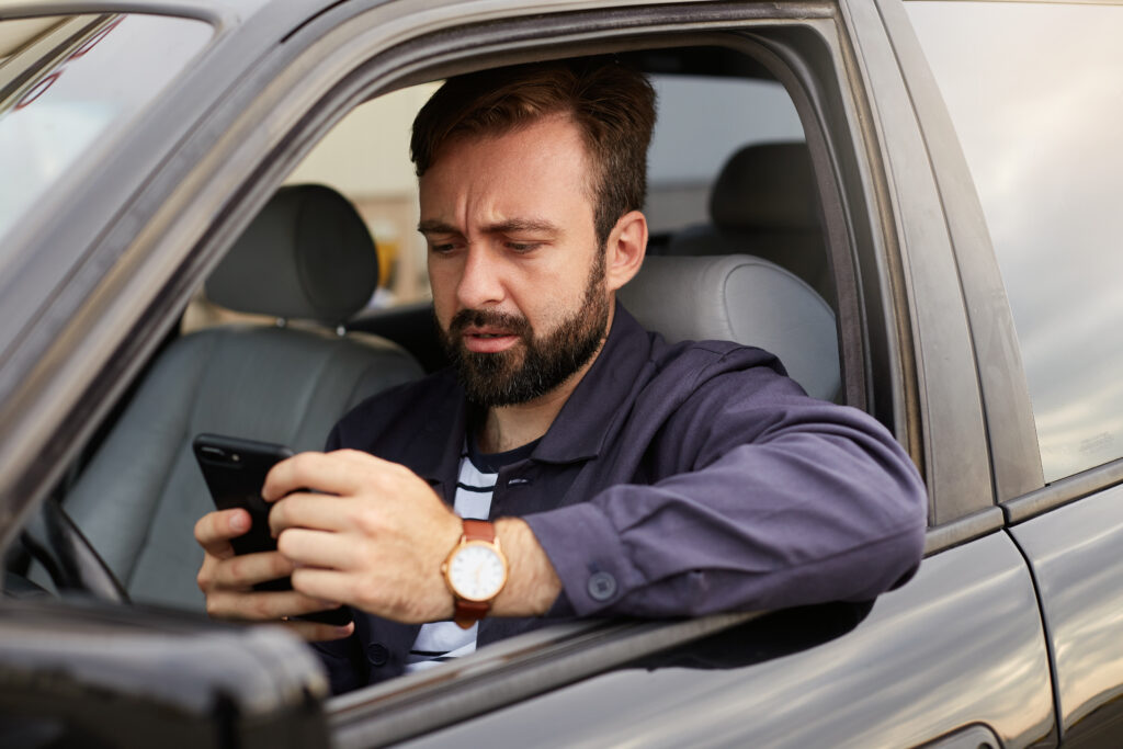Motorista em volante verificando o celular.