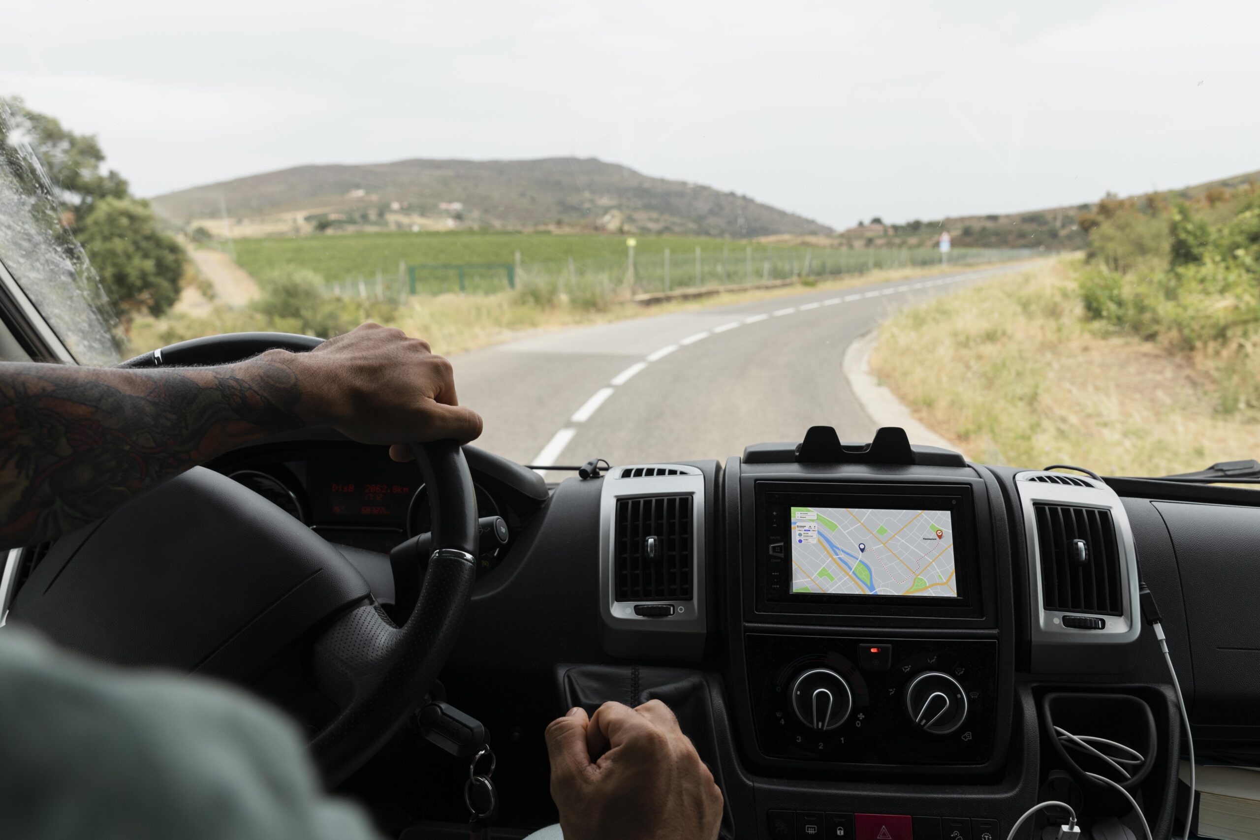 Motorista dirigindo na estrada, com GPS ao lado.