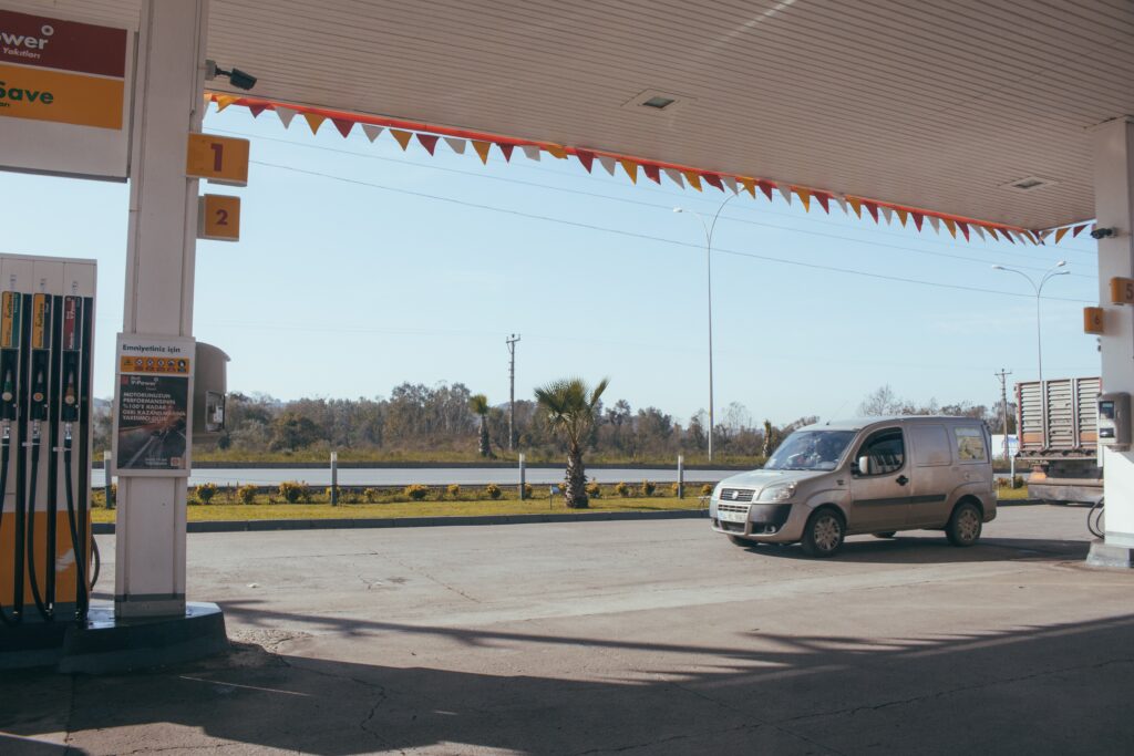 Posto de gasolina com bomba de combustível à esquerda, com um carro prata à direita.