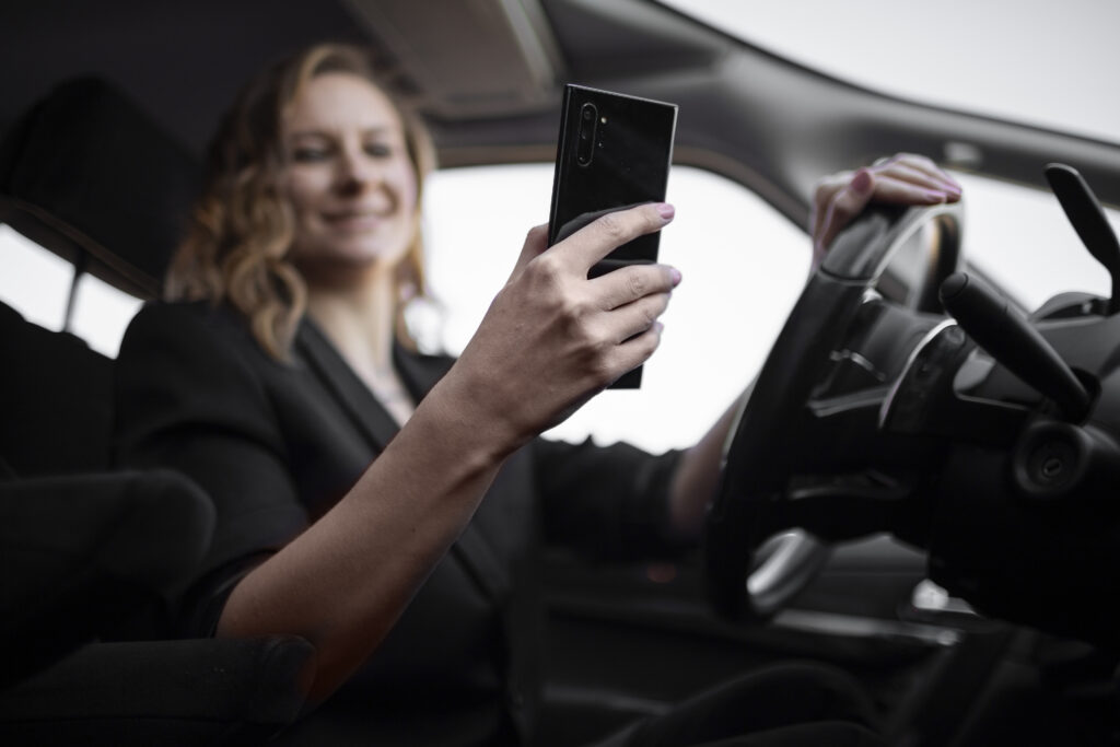Motorista dirigindo enquanto olha a tela do celular.