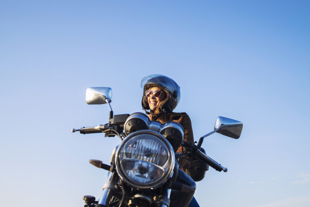 Mulher de capacete em uma moto preta.