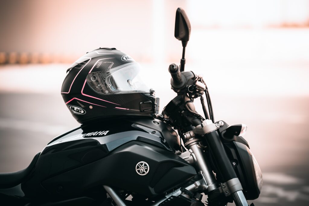Volante de uma moto Yamaha preta, com um capacete preto apoiado sobre a moto.