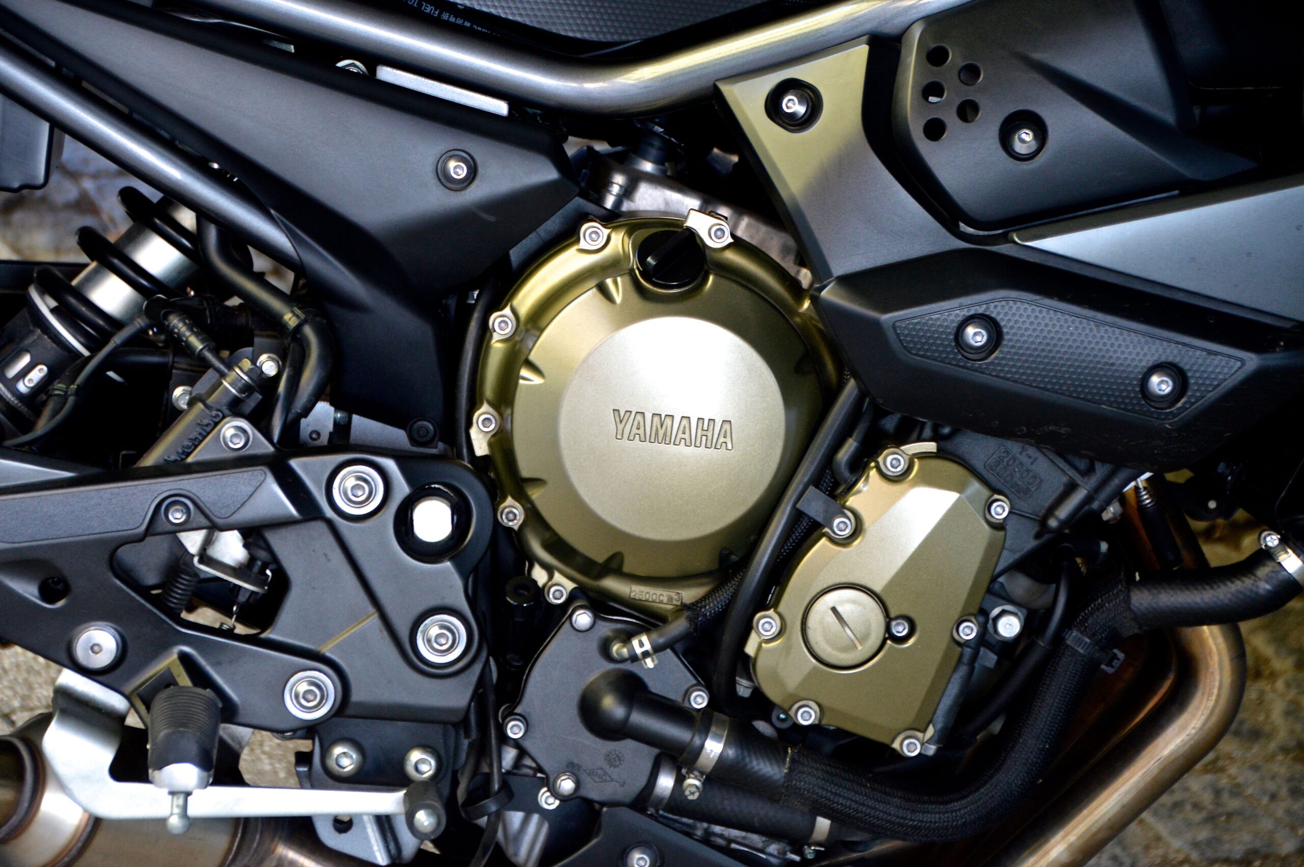 Imagem de parte de uma moto preta, tendo foco no motor escrito Yamaha.